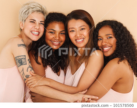 Four smiling diverse women embracing each other. Group of happy females of different races. 101578500