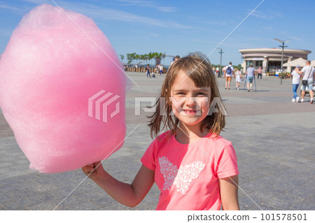 Happy girl holding cotton candy in an amusement park Happy girl holding cotton candy in an amusement park 101578501