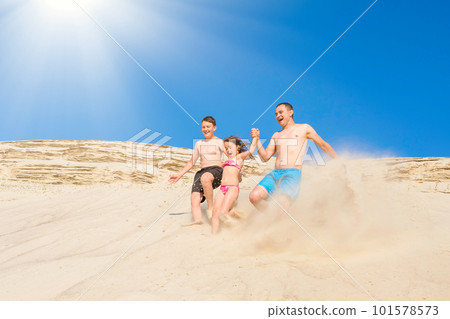 Happy family have fun running along the sand on the beach on a sunny summer day. Family vacation. Healthy lifestyle. Happy family have fun running along the sand on the beach on a sunny summer day. Family vacation. Healthy lifestyle. 101578573