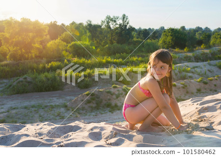 Little girl plays with sand on a summer beach on a sunny day. Active summer games. 101580462