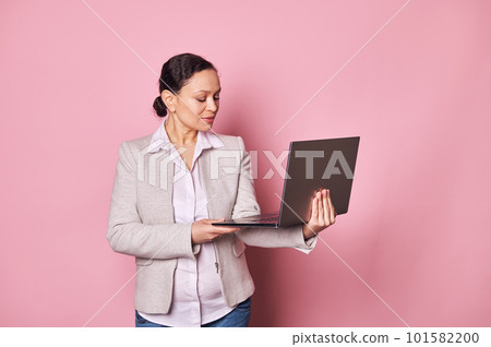 Confident middle aged brunette woman, programmer,business owner, sales manager, recruiter using laptop, online working, planning startup, telecommuting, isolated on pink background. People and career Confident middle aged brunette woman, programmer,business owner, sales manager, recruiter using laptop, online working, planning startup, telecommuting, isolated on pink background. People and career 101582200