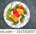 Red, yellow and green roasted mini peppers on plate, top view 101582657