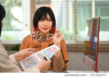Pretty young asian woman collaborating on new startup project with her colleague at creative workplace Pretty young asian woman collaborating on new startup project with her colleague at creative workplace 101582673