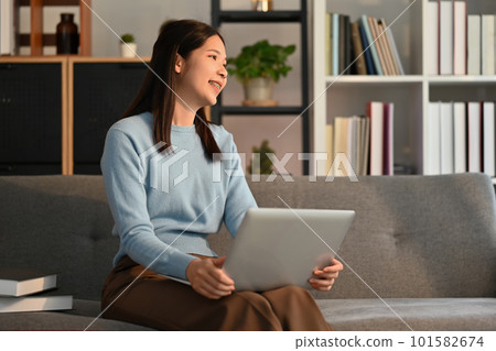 Nice asian woman using laptop computer on couch and smiling moment. Nice asian woman using laptop computer on couch and smiling moment. 101582674