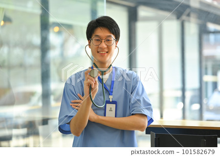 Portrait of doctor in blue uniform holding stethoscope in hand smiling to camera. Healthcare and medical concept 101582679
