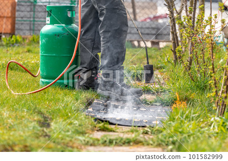 heating asphalt belts for waterproofing the foundation of the house with the help of a gas tank and an open fire 101582999