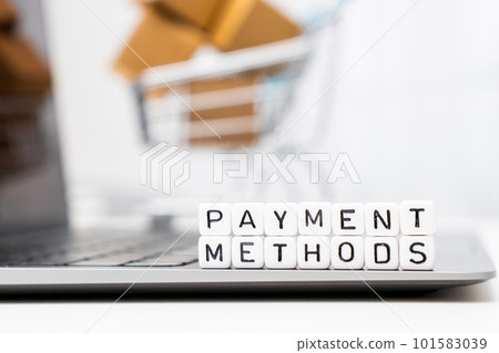 Payment methods words on cubes laying on the laptop and a toy shopping cart with carton boxes serves as the background. Payment methods words on cubes laying on the laptop and a toy shopping cart with carton boxes serves as the background. 101583039