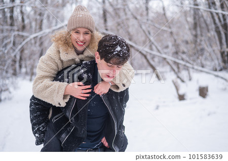 A young couple walks in the park in winter. Guy and girl hugging outdoors. A young couple walks in the park in winter. Guy and girl hugging outdoors. 101583639