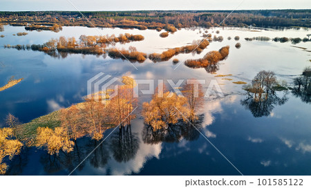 Spring flood rural landscape. Trees, meadow, bushes, fields, country road under High Water inundation. Sky and clouds reflection in evening light. Freshet Overflow aerial view. 101585122