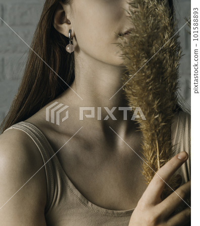 Beautiful earrings with a pink stone and the ears of a girl with a long neck and a bouquet of dried flowers Beautiful earrings with a pink stone and the ears of a girl with a long neck and a bouquet of dried flowers 101588893