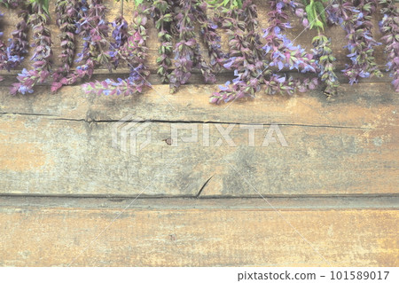 Lavender and sage flowers on a wooden table close-up. Horizontal planks of dark old wood with purple and blue flowers and leaves around the edges. Still life and flat lay. Free copy space for text 101589017