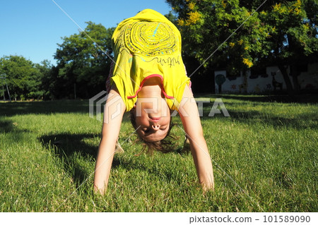 Caucasian girl 8 years old doing a bridge exercise on the grass in the park. Playground. Children's sports. Spine health, treatment of scoliosis 101589090