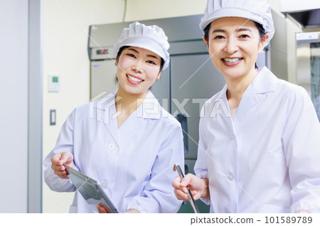一位身穿白大褂的女廚師在廚房做飯 101589789