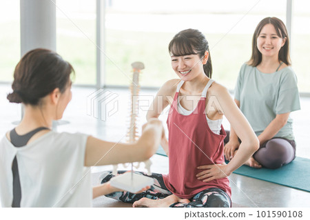 Women doing yoga while looking at the pelvis, coccyx, and skeleton sample 101590108
