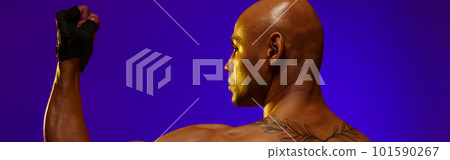Sporty musculed man demonstrate biceps on studio background with color filter 101590267