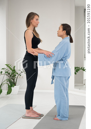 Caucasian woman stands on sadhu boards with therapist support. Caucasian woman stands on sadhu boards with therapist support. 101591190
