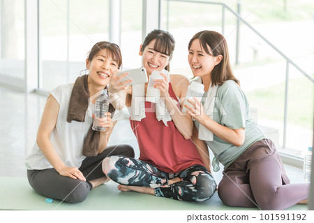女性在體育館瑜伽課休息時用智能手機拍照 女性在體育館瑜伽課休息時用智能手機拍照 101591192