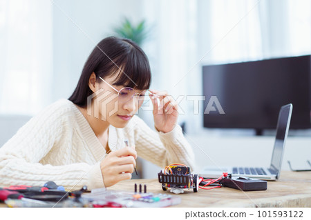 Happy cheerful Asian ethnicity female university student learning about robotic and programing by herself, woman assemble a robot and coding. 101593122