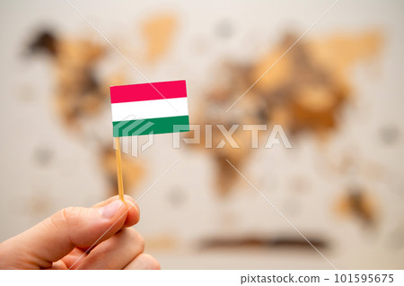 Hungary flag in mans hand on the wooden world map background. Global economy and geopolitics concept. Hungary flag in mans hand on the wooden world map background. Global economy and geopolitics concept. 101595675