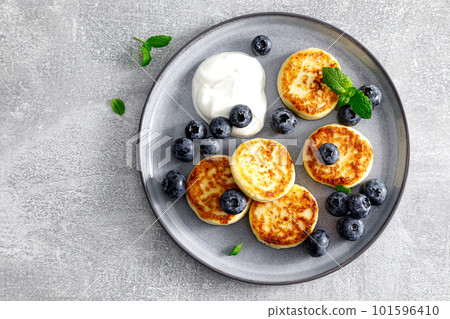 Cottage cheese fritters with fresh blueberry and yogurt for breakfast, copy space, view from above 101596410
