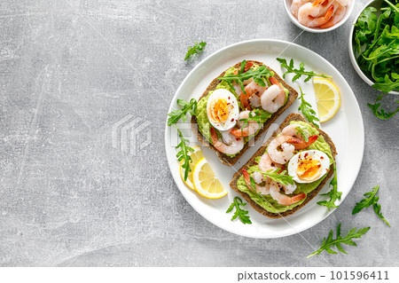Toast with shrimps, avocado guacomole, arugula and boiled egg, top view Toast with shrimps, avocado guacomole, arugula and boiled egg, top view 101596411