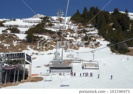 Ski lifts with tourists on snow covered land with mountains in background during winter vacation, winter holiday travel concept Ski lifts with tourists on snow covered land with mountains in background during winter vacation, winter holiday travel concept 101596973