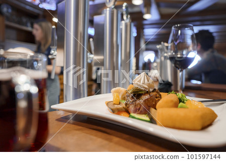 Closeup of fresh food with garnish served in plate kept in front of wineglass on table at restaurant, winter holiday travel concept 101597144