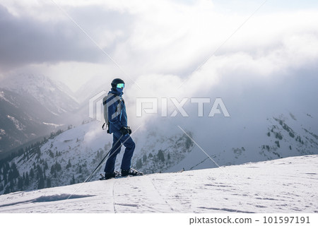 Tourist with ski poles skiing on snow covered mountain with cloudy sky in background during winter vacation, winter holiday travel concept 101597191