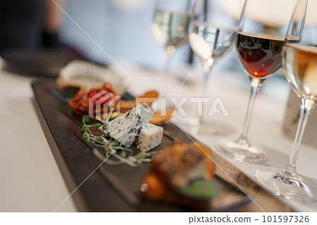 Closeup of wineglasses served with various delicious appetizers on dining table at modern restaurant in luxurious hotel, luxury travel concept for tourists 101597326