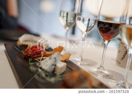 Closeup of wineglasses with various delicious appetizers served in plate on dining table at luxurious restaurant in modern hotel, luxury travel concept for tourists 101597328