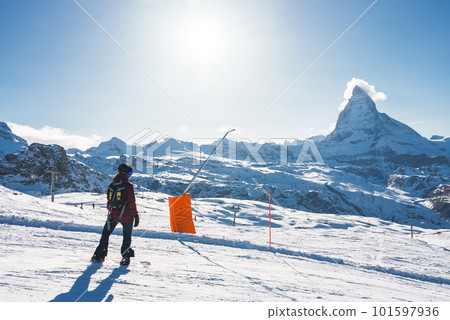 Young man snowboarding in Zermatt ski resort right next to the famous Matterhorn peak. Beautiful sunny day for snowboarding. Winter sports concept. 101597936