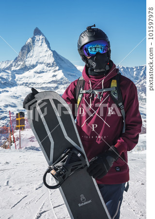 Young snowboarder spending winter holidays in Zermatt, near the famous Matterhorn peak. Male posing in Swiss Alps for the snowboarding season. Young snowboarder spending winter holidays in Zermatt, near the famous Matterhorn peak. Male posing in Swiss Alps for the snowboarding season. 101597978