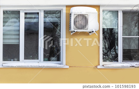 An air conditioner is installed on the wall of the residential building. Winter and snow-covered  101598193
