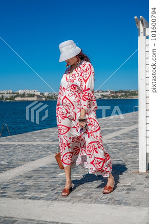 woman in a hat and dress enjoys the blue sea and summer. Welcome summer. 101600794