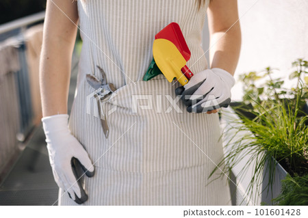 Middle selection of female in overall with garden tools stand on balcony and preparing for landing Middle selection of female in overall with garden tools stand on balcony and preparing for landing 101601428