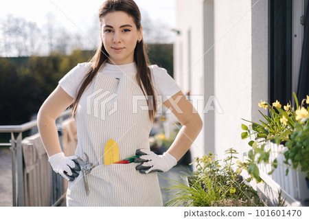 Portrait of beautiful woman in overall with garden tools stand at balcony and preparing for landing. relaxing after working day. Portrait of beautiful woman in overall with garden tools stand at balcony and preparing for landing. relaxing after working day. 101601470