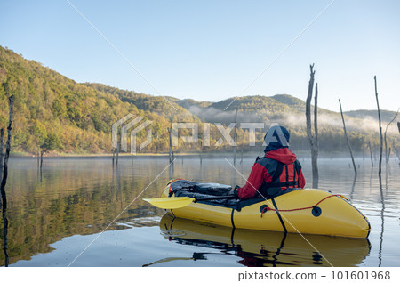 A person riding a packraft floating on a clear stream A person riding a packraft floating on a clear stream 101601968
