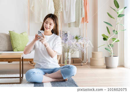 年輕女子在客廳看智慧型手機 101602075