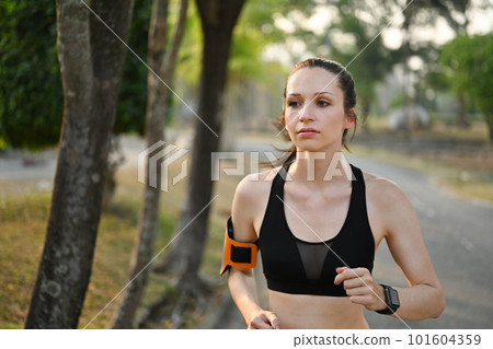 Delighted athletic woman in sportswear jogging in public park. Healthy lifestyle, sport, wellness concept Delighted athletic woman in sportswear jogging in public park. Healthy lifestyle, sport, wellness concept 101604359