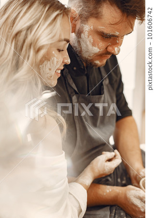 Mutual creative work. Young beautiful couple in casual clothes and aprons. People creating a bowl on a pottery wheel in a clay studio. Mutual creative work. Young beautiful couple in casual clothes and aprons. People creating a bowl on a pottery wheel in a clay studio. 101606742