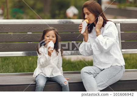 Family in a city. Little girl eats ice cream. Mother with daughter sitting on a bench. Family in a city. Little girl eats ice cream. Mother with daughter sitting on a bench. 101606942