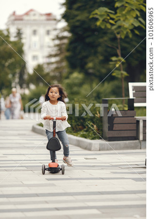 Child on kick scooter in park. Kids learn to skate roller board. Little girl skating on sunny summer day. Child on kick scooter in park. Kids learn to skate roller board. Little girl skating on sunny summer day. 101606965