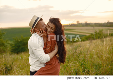 Couple in a field. Woman in a brown dress. Sunset background. 101606978
