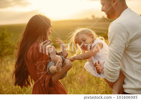 Family with cute little child. Father in a white shirt. Sunset background. 101606985