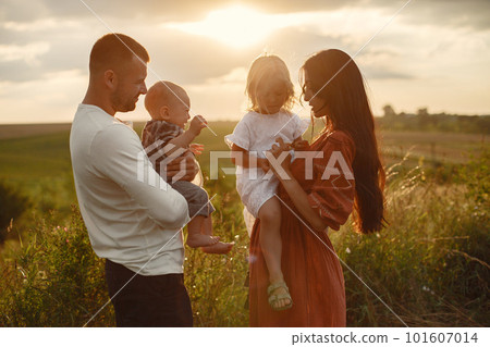 Family with cute little child. Father in a white shirt. Sunset background. 101607014
