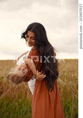 Family in a summer field. Mother in a brown dress. Cute little girl. 101607017
