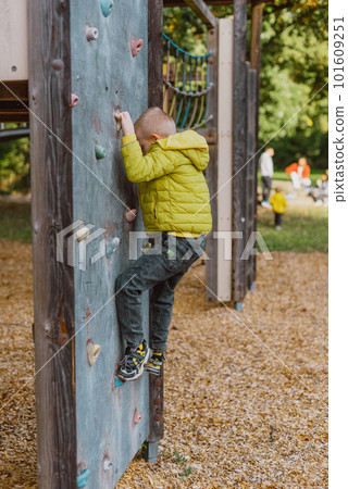 Boy At The Climbing Wall Without A Helmet, Danger At The Climbing Wall. Little Boy Climbing A Rock Wall Indoor Boy At The Climbing Wall Without A Helmet, Danger At The Climbing Wall. Little Boy Climbing A Rock Wall Indoor 101609251