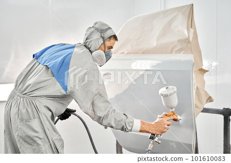 Painting the rear door of the car. Car painter in special painting chamber, wearing costume and protective gear. Car service station. Restoring a car after an accident 101610083