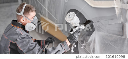 Painting the rear part of the car. Car painter wearing costume and protective gear. Car service station. Restoring a car after an accident Painting the rear part of the car. Car painter wearing costume and protective gear. Car service station. Restoring a car after an accident 101610096