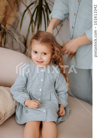 Young mother braiding little daughter's hair 101611042